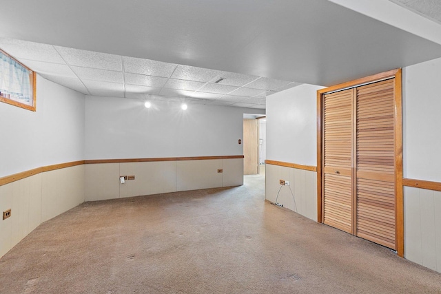 basement featuring light carpet and a paneled ceiling