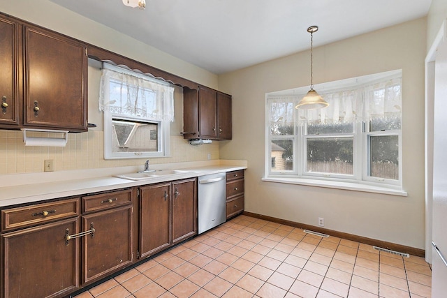 kitchen featuring pendant lighting, sink, backsplash, stainless steel dishwasher, and dark brown cabinetry