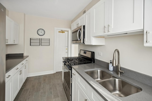 kitchen with white cabinets, appliances with stainless steel finishes, dark hardwood / wood-style flooring, and sink