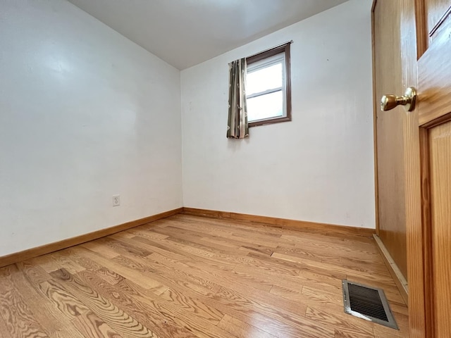 spare room with light wood-type flooring and vaulted ceiling