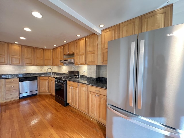 kitchen with tasteful backsplash, sink, light hardwood / wood-style flooring, appliances with stainless steel finishes, and dark stone counters