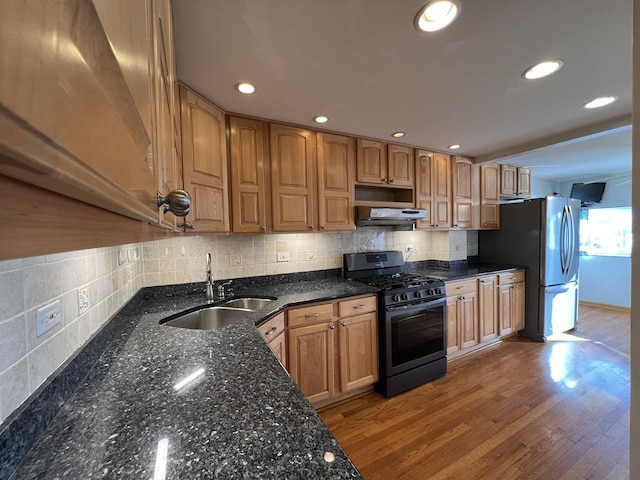 kitchen featuring decorative backsplash, sink, light hardwood / wood-style flooring, black range with gas cooktop, and stainless steel fridge