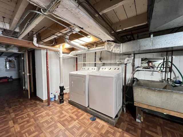 clothes washing area featuring sink, washing machine and clothes dryer, and parquet flooring