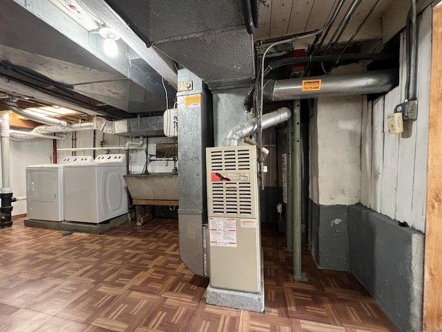 utility room featuring heating unit, washing machine and dryer, and sink