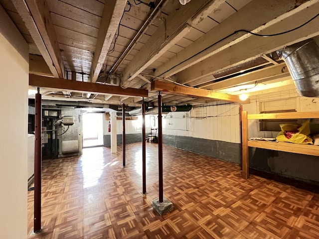 basement featuring heating unit and dark parquet flooring