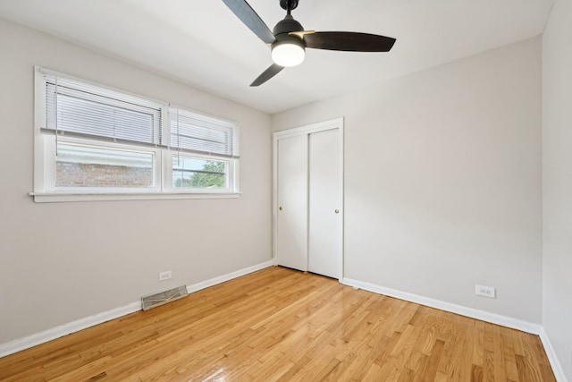 unfurnished bedroom featuring ceiling fan, a closet, and light wood-type flooring