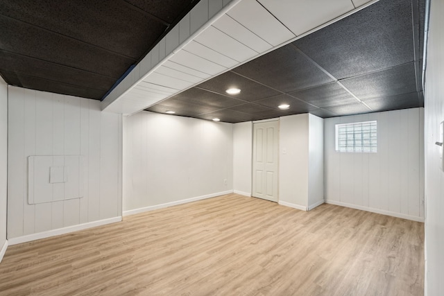 basement featuring a paneled ceiling and light hardwood / wood-style floors