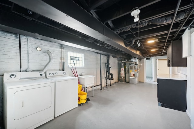 basement with sink, heating unit, washer and clothes dryer, and gas water heater