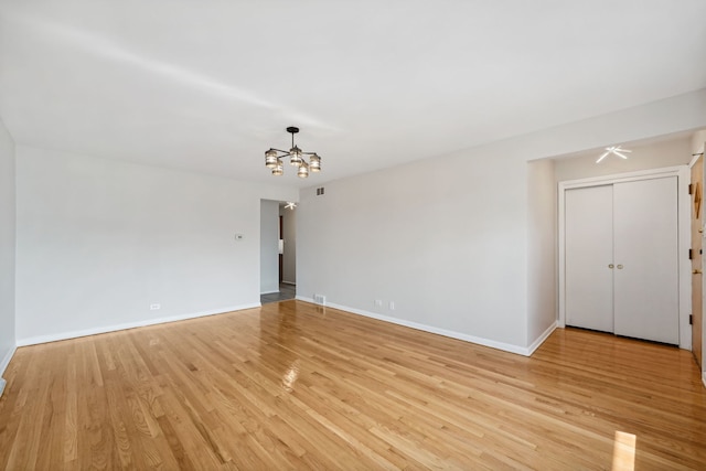 unfurnished room featuring light wood-type flooring and a notable chandelier