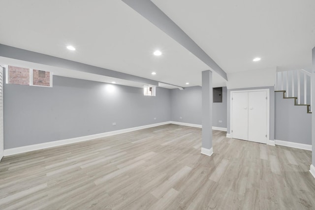 basement featuring light wood-type flooring and electric panel