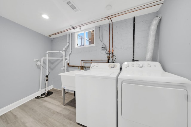 laundry area featuring light hardwood / wood-style floors, sink, and washer and clothes dryer