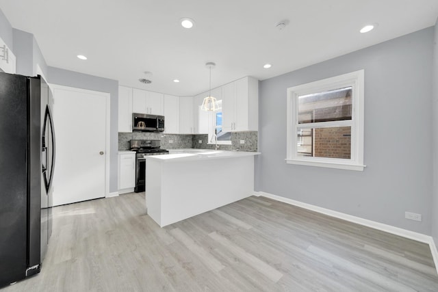 kitchen with kitchen peninsula, appliances with stainless steel finishes, white cabinetry, and hanging light fixtures