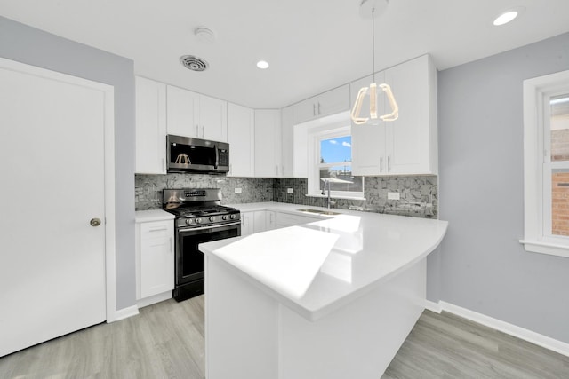 kitchen with hanging light fixtures, white cabinets, sink, and stainless steel appliances