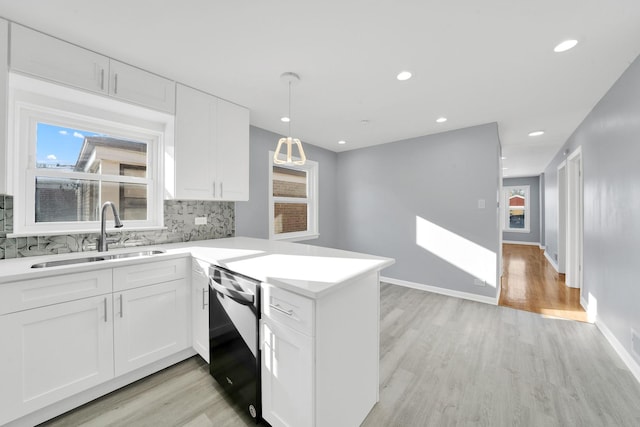 kitchen with kitchen peninsula, dishwasher, sink, and white cabinetry