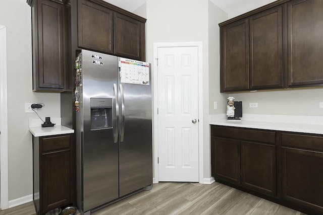 kitchen featuring light wood-type flooring, stainless steel refrigerator with ice dispenser, and dark brown cabinetry