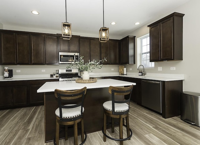 kitchen featuring appliances with stainless steel finishes, hardwood / wood-style flooring, hanging light fixtures, and a kitchen island