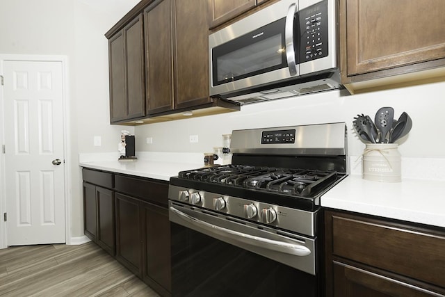 kitchen with dark brown cabinets, stainless steel appliances, and light hardwood / wood-style floors