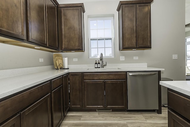 kitchen with sink, dark brown cabinetry, stainless steel dishwasher, and light hardwood / wood-style flooring