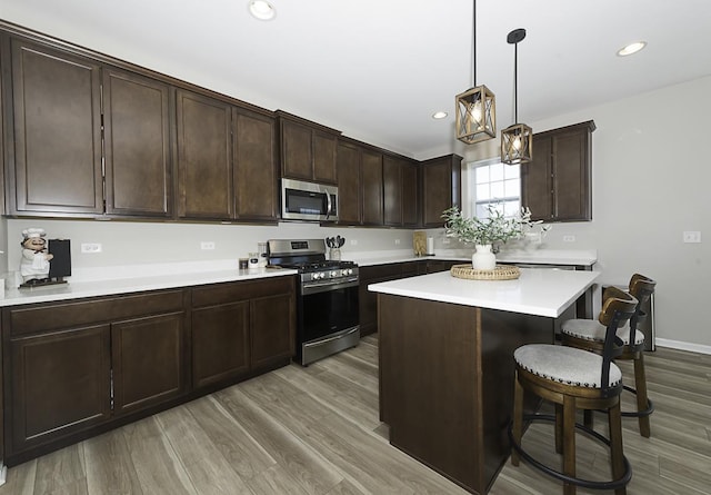 kitchen with decorative light fixtures, a kitchen island, hardwood / wood-style flooring, stainless steel appliances, and dark brown cabinets