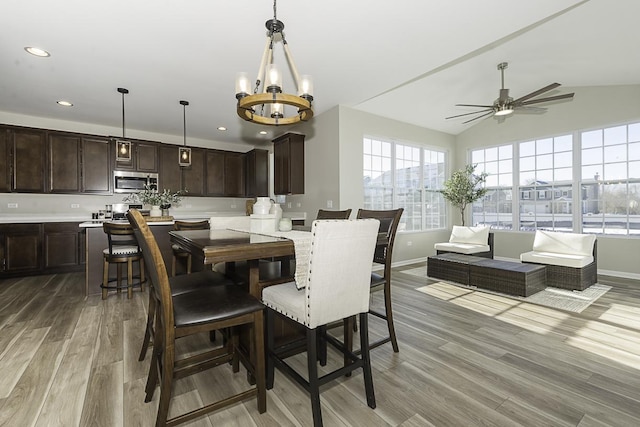 dining space featuring ceiling fan with notable chandelier, light hardwood / wood-style flooring, and lofted ceiling