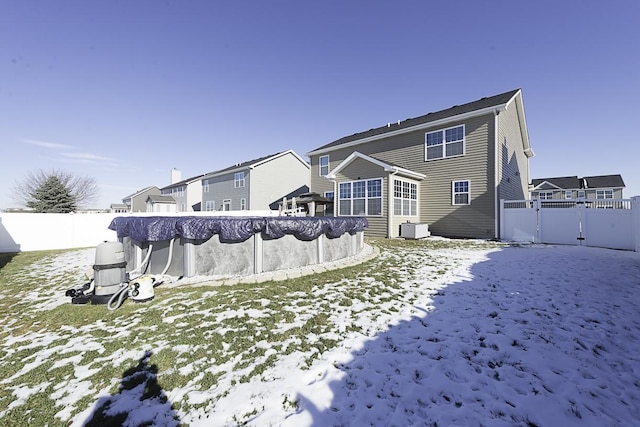 snow covered back of property with a covered pool