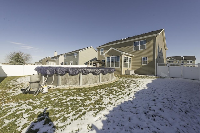 snow covered rear of property featuring a covered pool