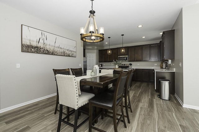 dining area featuring sink, wood-type flooring, and a notable chandelier