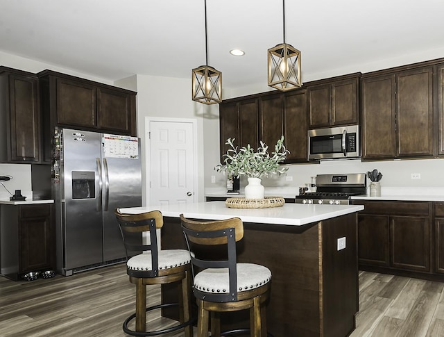 kitchen with decorative light fixtures, dark brown cabinetry, appliances with stainless steel finishes, and dark hardwood / wood-style flooring