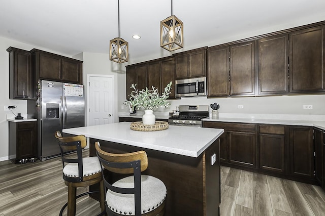 kitchen featuring dark hardwood / wood-style floors, a center island, dark brown cabinetry, hanging light fixtures, and appliances with stainless steel finishes