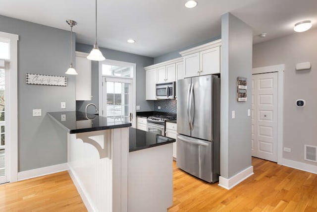 kitchen with white cabinets, appliances with stainless steel finishes, decorative light fixtures, decorative backsplash, and kitchen peninsula