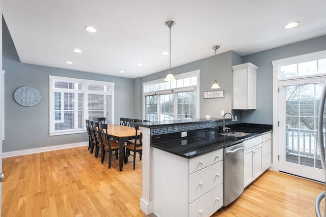 kitchen with decorative light fixtures, white cabinetry, light hardwood / wood-style floors, sink, and stainless steel dishwasher