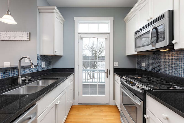 kitchen featuring dark stone counters, sink, stainless steel appliances, and white cabinetry