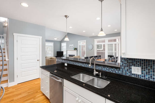 kitchen featuring decorative light fixtures, white cabinets, dishwasher, and sink