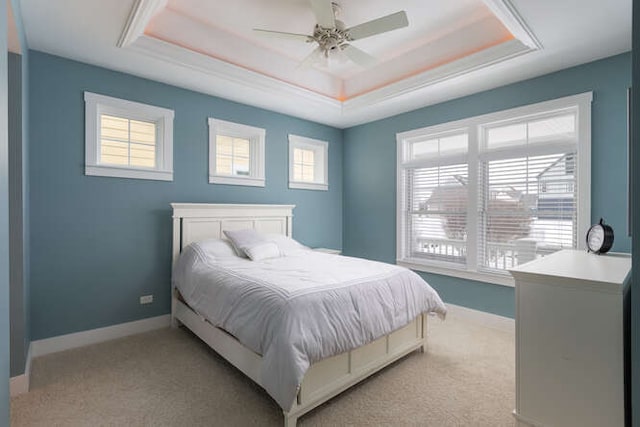 bedroom with a raised ceiling, ceiling fan, and multiple windows