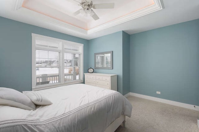 bedroom featuring ceiling fan, light carpet, and a tray ceiling