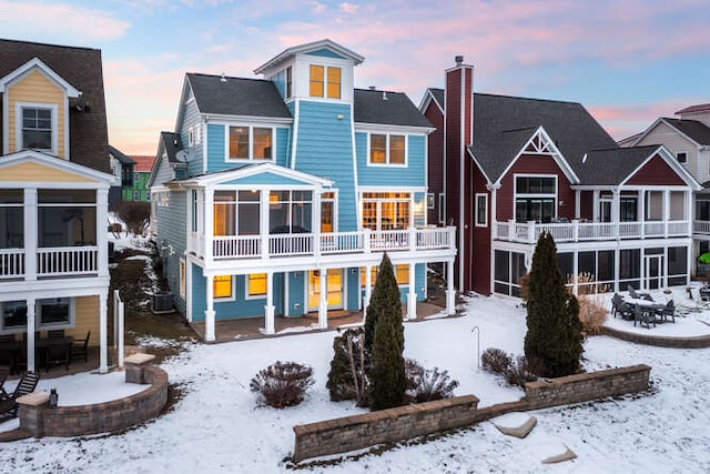 snow covered house with cooling unit and a sunroom