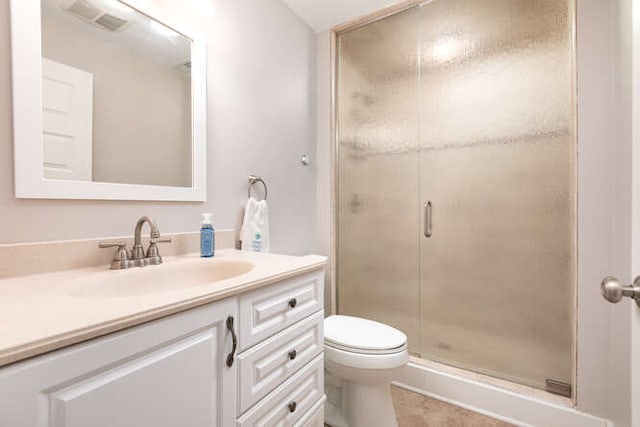 bathroom featuring an enclosed shower, vanity, toilet, and tile patterned flooring