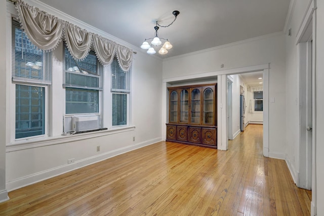 unfurnished dining area with crown molding, a chandelier, and light hardwood / wood-style flooring