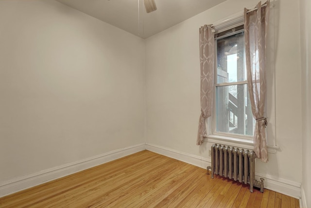 unfurnished room with ceiling fan, radiator heating unit, and light hardwood / wood-style flooring