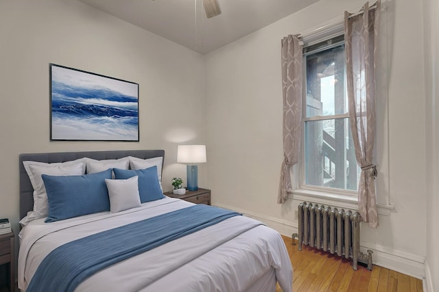 bedroom featuring ceiling fan, wood-type flooring, and radiator heating unit