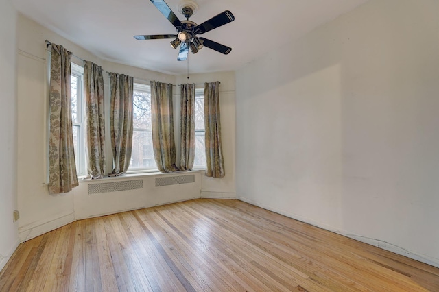 spare room featuring ceiling fan, light hardwood / wood-style floors, and radiator