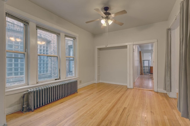 spare room with ceiling fan, radiator heating unit, and light hardwood / wood-style floors