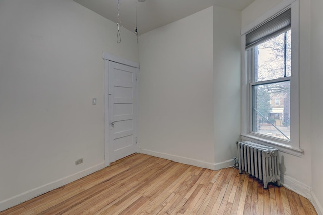 unfurnished room with radiator and light wood-type flooring