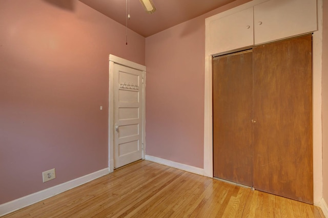 unfurnished bedroom with ceiling fan, light wood-type flooring, and a closet