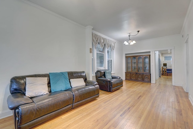 living room with light hardwood / wood-style floors, ornamental molding, and an inviting chandelier