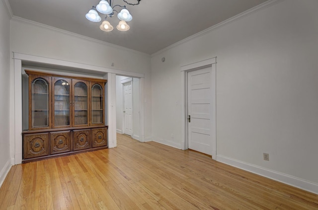 empty room featuring light hardwood / wood-style floors, ornamental molding, and a chandelier