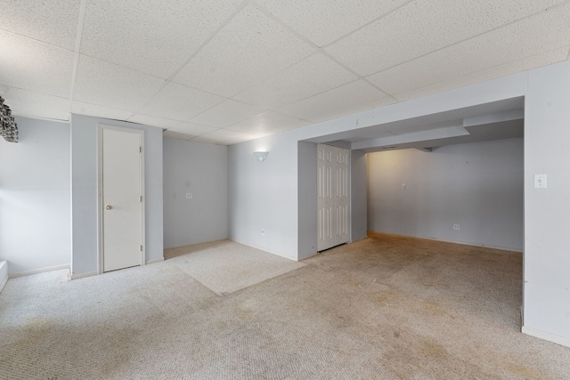 basement featuring light colored carpet and a paneled ceiling