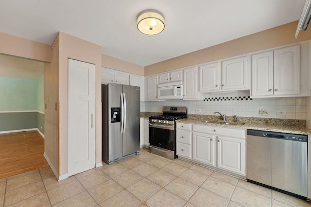 kitchen with appliances with stainless steel finishes, white cabinetry, light stone counters, and sink