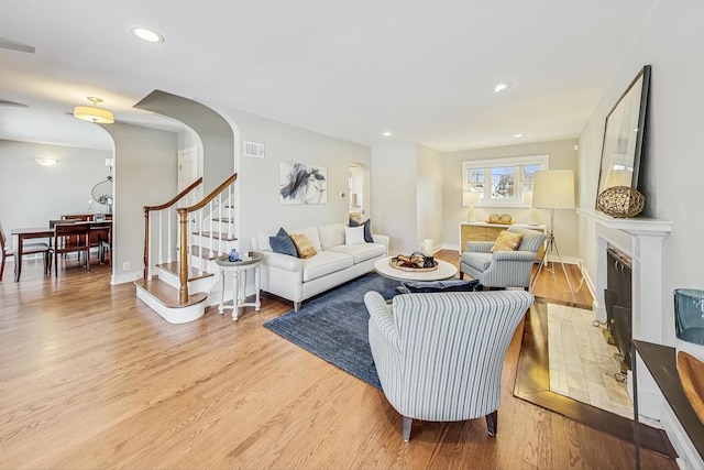 living room with a tile fireplace and light hardwood / wood-style flooring