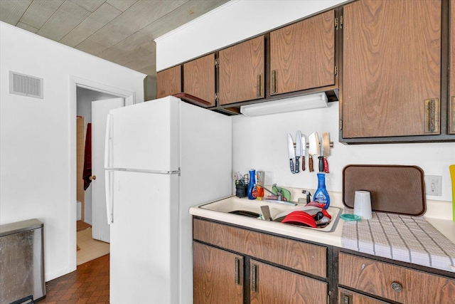 kitchen featuring sink, white fridge, and wooden ceiling